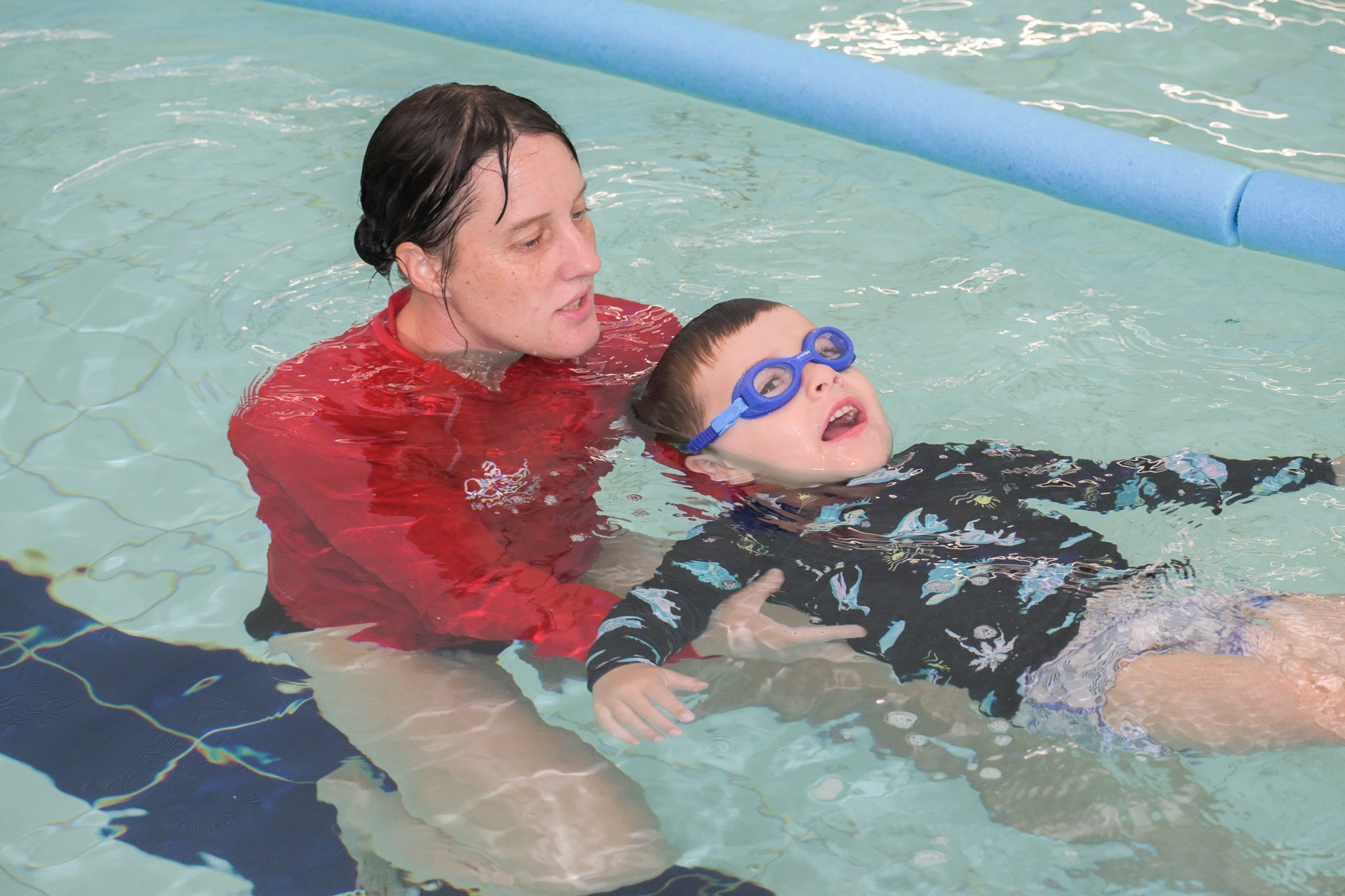 Instructor supports the head a boy floating in the water