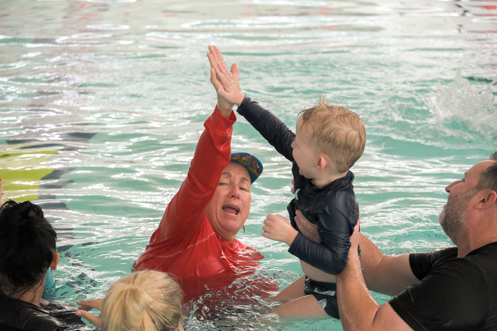 Instructor high fives young boy at the end of a swimming lesson